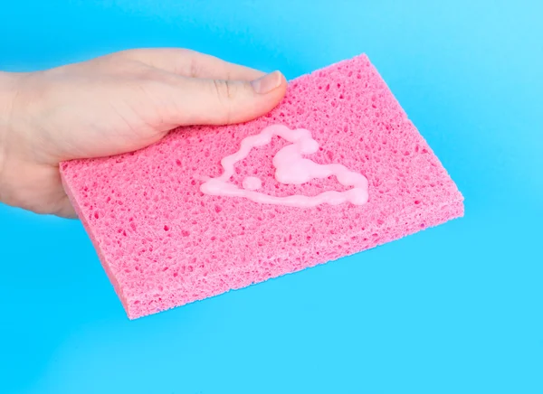 Esponja en mano con detergente sobre fondo azul —  Fotos de Stock