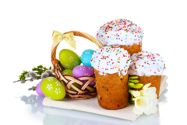 Beautiful Easter cakes, colorful eggs in basket and flowers isolated on white