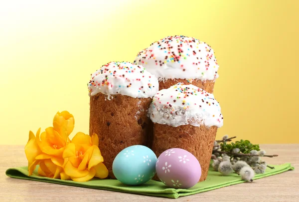 아름 다운 부활절 케이크, 다채로운 계란과 노란색 배경에 나무 테이블에 여자-버드 나무 잔 가지 — 스톡 사진