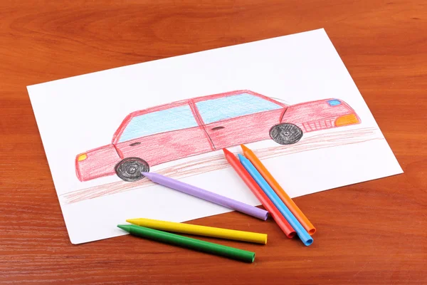 Children's drawing of red car and pencils on wooden background — Stock Photo, Image