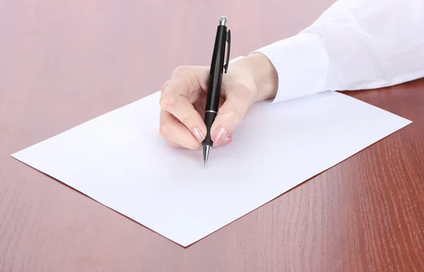 Kobieta w zapasie pismo na papierze, na drewnianym stole — Zdjęcie stockowe