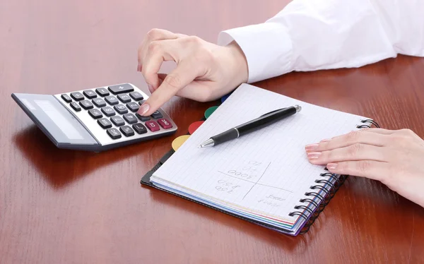 Women hands with pencil, notebook and Calculator on wooden table — Stock Photo, Image