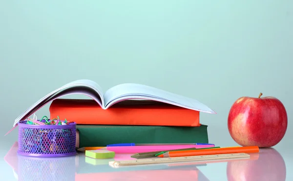 Összetételét könyvek, papíráruk és egy almát, színes háttérrel — Stock Fotó