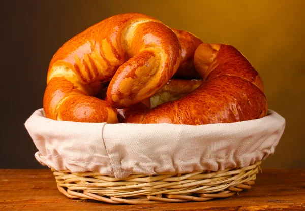 Gebackenes Brot im Korb auf Holztisch auf braunem Hintergrund — Stockfoto