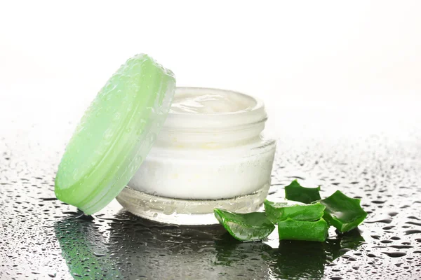 Opened glass jar of cream and aloe on black and white background with water droplets — Stock Photo, Image