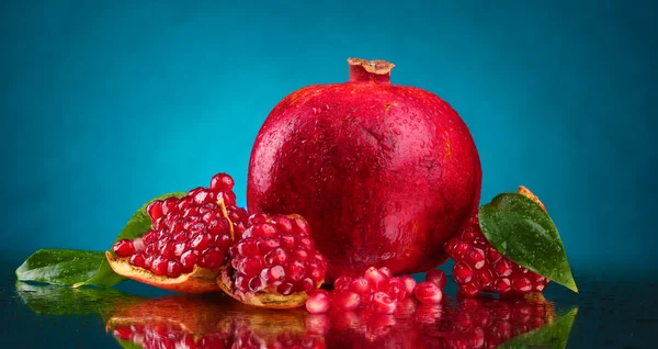 Mogen granatäpple frukt med lämnar på blå bakgrund — Stockfoto