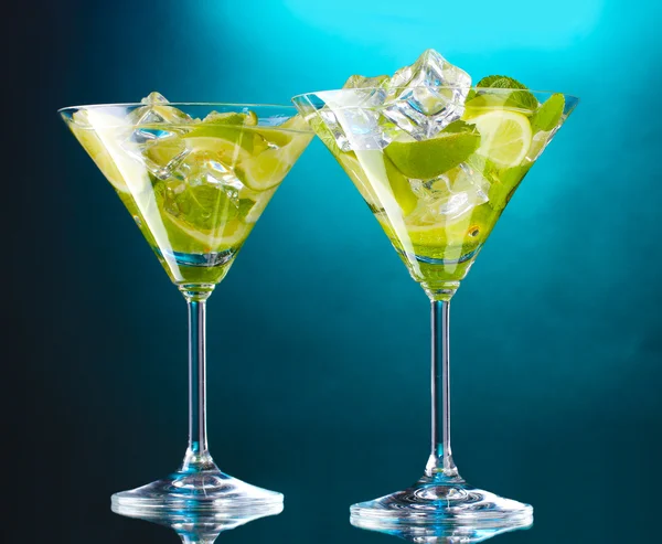 Glasses of cocktails with lime and mint on blue background — Stock Photo, Image