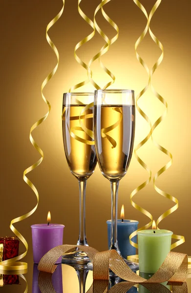 Şampanya, mum, hediyeler ve Sarı zemin üzerine flama gözlük — Stok fotoğraf