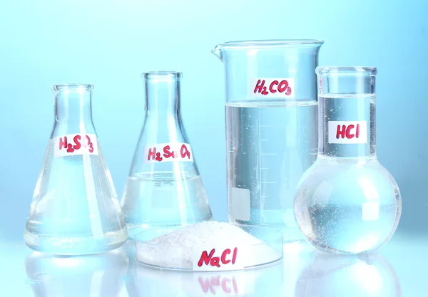 Probówki z różnych kwasów i środków chemicznych na niebieskim tle — Zdjęcie stockowe