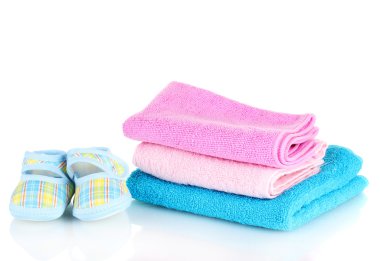 Blue baby booties and three colorful towels isolated on white