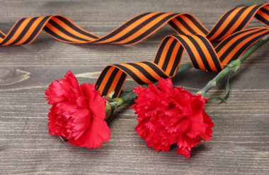 Carnations and St. George's ribbon on grey wooden background clipart
