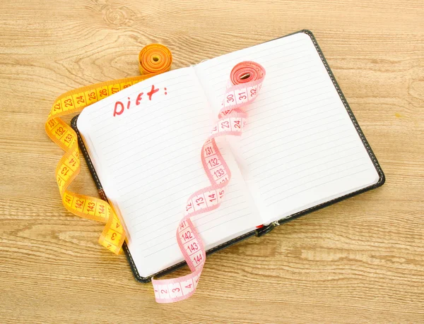Planning of diet. Notebook and measuring tapes on wooden table — Stock Photo, Image