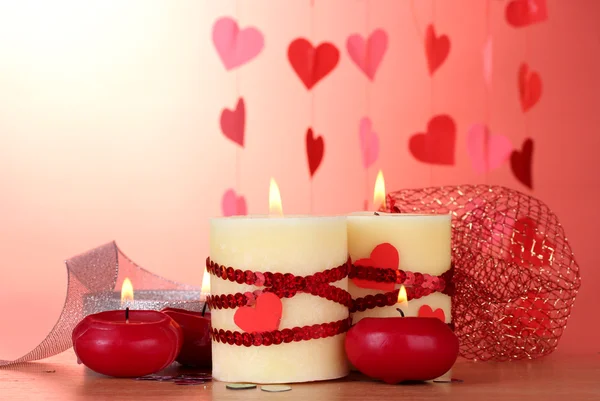 Świece na Walentynki na drewnianym stole na czerwonym tle — Zdjęcie stockowe