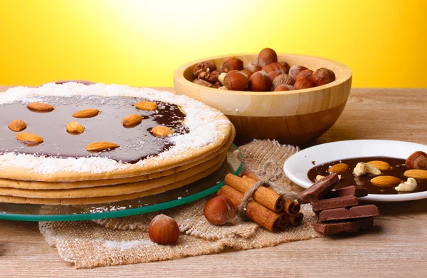 Tårta på glas stå och nötter på träbord på gul bakgrund — Stockfoto