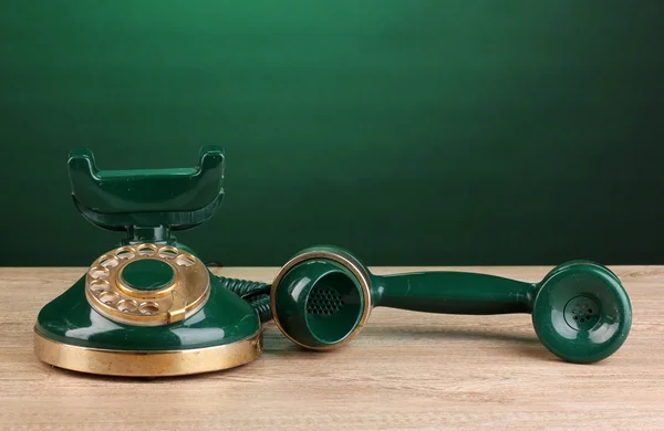 Retro phone on wooden table on green background — Stock Photo, Image
