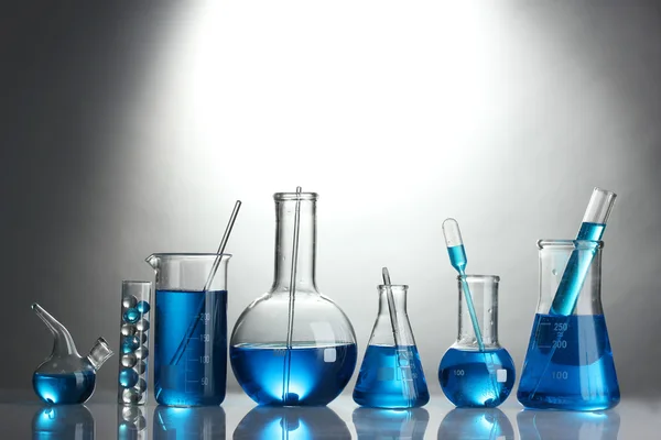 회색 배경에 파란색 액체와 시험관 — 스톡 사진