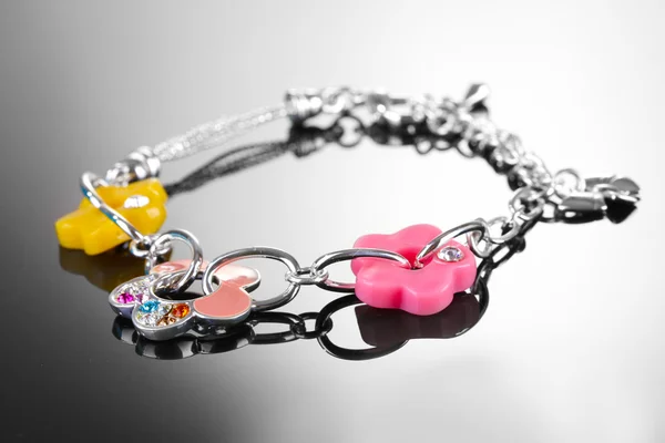 Beautiful silver bracelet with bright flowetrs on grey background — Stock Photo, Image