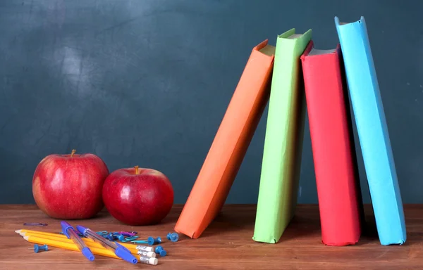 Kitap, kırtasiye ve öğretmen Masası blackboard arka planda bir elma bileşimi — Stok fotoğraf