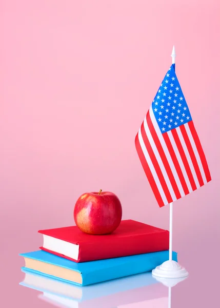 Composición de la bandera americana, un par de libros y manzana sobre fondo colorido —  Fotos de Stock