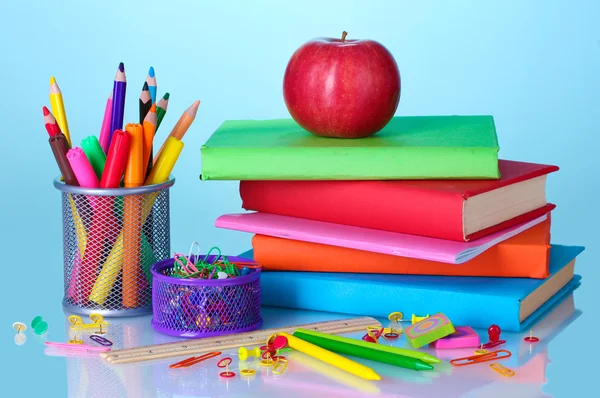 Composición de libros, papelería y una manzana sobre fondo de colores brillantes — Foto de Stock