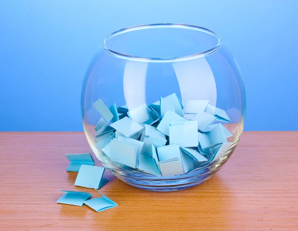 Шматочки паперу для лотереї у вазі на дерев'яному столі на синьому фоні — стокове фото