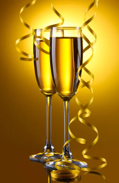 Copos de champanhe e streamer no fundo amarelo — Fotografia de Stock