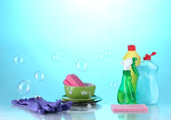 Lavando platos. Productos de limpieza sobre fondo azul brillante — Foto de Stock