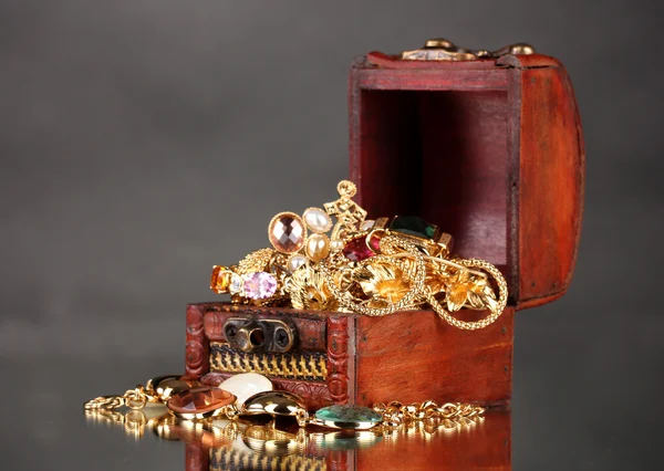 Drewniana skrzynia pełna Biżuteria złota na szarym tle — Zdjęcie stockowe