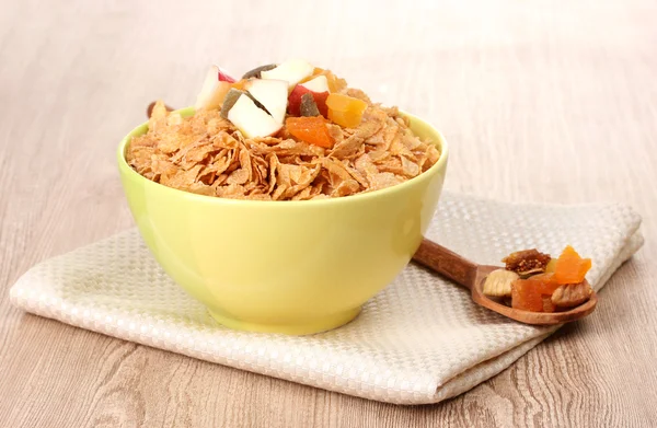 Tasty cornflakes in bowl with dried fruits on wooden table — Stock Photo, Image