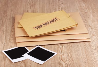 Envelopes with top secret stamp with photo papers on wooden background clipart