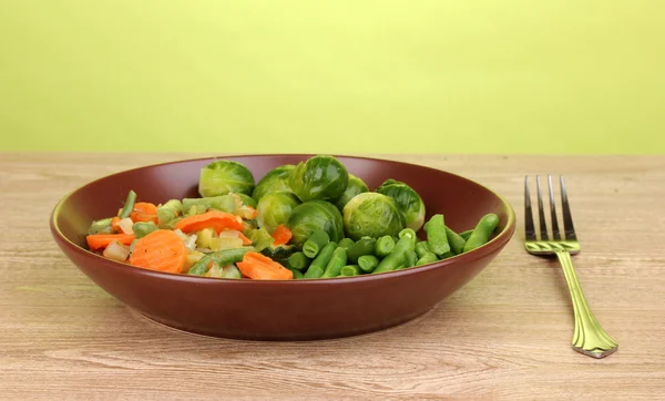 緑色の背景で木製のテーブルの上皿に野菜 — ストック写真
