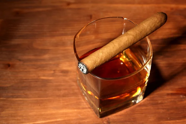 Dwie szklanki whisky i cygara w drewnianym stołem — Zdjęcie stockowe