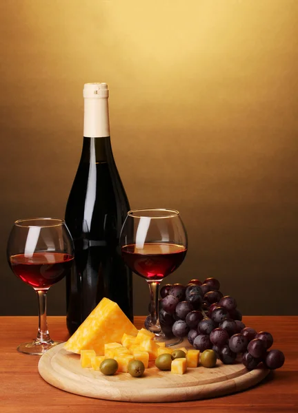 Botella de gran vino con gafas de vino y queso sobre mesa de madera sobre fondo marrón — Foto de Stock