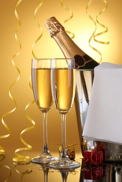 Бутылка шампанского в ведре со льдом и бокалами шампанского, на желтом фоне — стоковое фото
