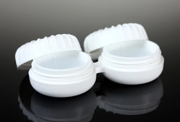 Contact lenses in containers on grey background — Stock Photo, Image
