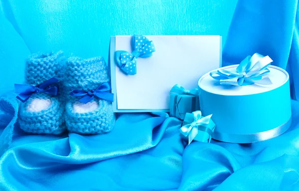 Belos presentes, babys bootees, cartão postal em branco e boneco em seda azul — Fotografia de Stock