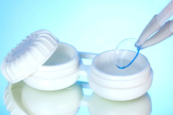 Kontaktlinser i behållare och pincett på blå bakgrund — Stockfoto