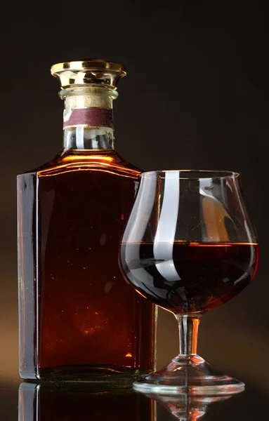 Стакан бренди и бутылка на коричневом фоне — стоковое фото