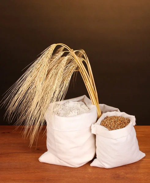Grão de farinha e trigo na mesa de madeira no fundo escuro — Fotografia de Stock