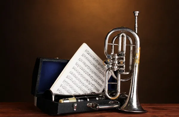 Antika trumpet och klarinett i fall på träbord på brun bakgrund — Stockfoto