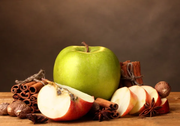 Cinnamon sticks,apples nutmeg and anise on wooden table on brown background — Stock Photo, Image