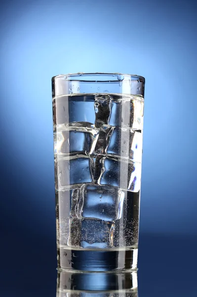 Vaso de agua con hielo sobre fondo azul — Foto de Stock