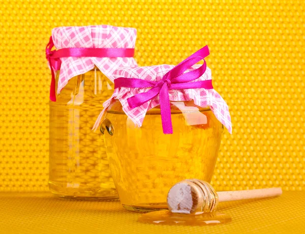 Frascos de miel y rociador de madera sobre fondo de panal amarillo — Foto de Stock