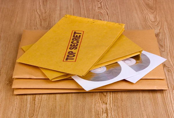 Buste con timbro top secret con dischi CD su sfondo di legno — Foto Stock