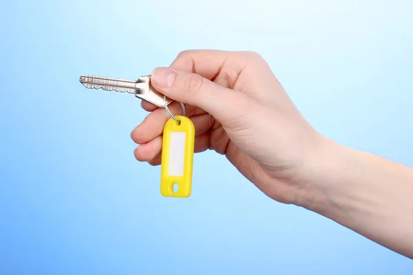 Key in hand on blue background — Stock Photo, Image