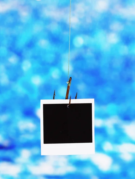 Photo on fish hook on blue background — Stock Photo, Image