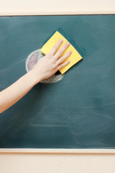 Hand met een gele spons reinigen van het schoolbord — Stockfoto