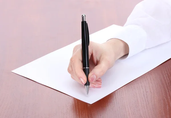 Kobieta w zapasie pismo na papierze, na drewnianym stole — Zdjęcie stockowe