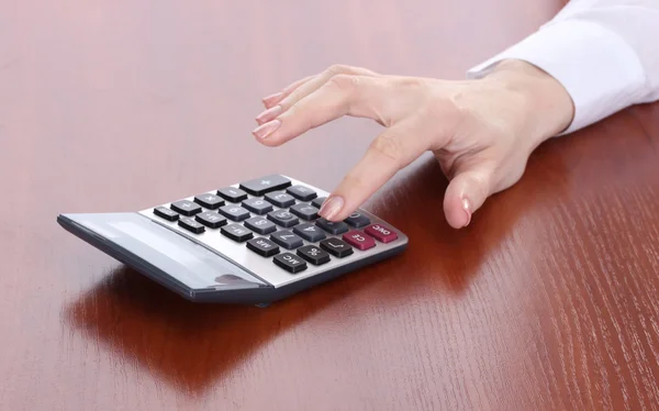 Женская рука и калькулятор на деревянном столе — стоковое фото