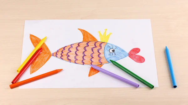 Childrens drawing of golden fish and pencils on wooden background — Stock Photo, Image
